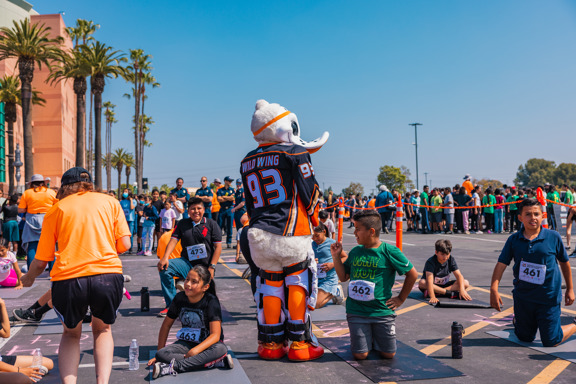 Wild Wing standing around students sitting on yoga mats 