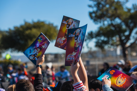 Student hands holding up First Flight workbooks